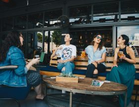 Foto de um grupo de mulheres que saíram do trabalho para o happy hour, todas com looks elegantes.