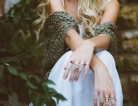 Foto de uma mulher sentada com um xale e anéis nos dedos em referencia ao estilo boho.