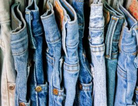 Foto de um varal com várias roupas jeans de cores variadas.