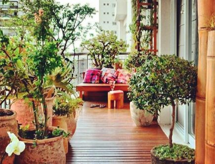 Foto de uma varanda pequena com plantas e um banco com almofadas rosa.
