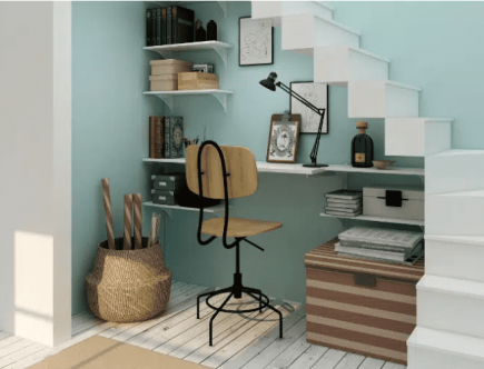 Foto de um escritório debaixo da escada, com prateleiras na parede e uma cadeira de rodinhas.