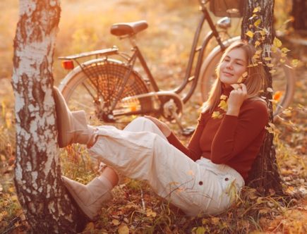 Foto de uma mulher entre a natureza no outono, vestida com estilos urbano.