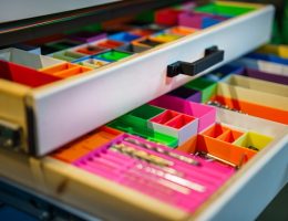 Foto de uma gaveta bem organizada com divisórias coloridas.