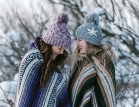 Foto de duas mulheres com look de inverno, com casaco e cachecol.