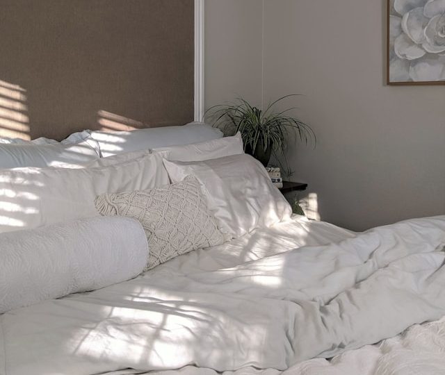 Foto de uma cama de casal com roupa de cama branca.
