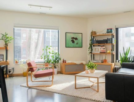 Foto de uma sala da estar com grandes janelas, móveis na cor clara e paredes bege.