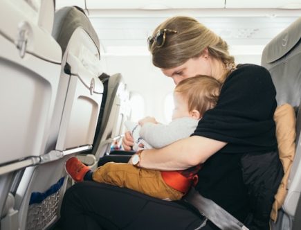 Foto de uma mulher dentro do avião viajando com criança de colo.