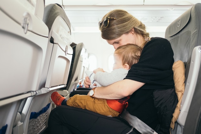 Foto de uma mulher dentro do avião viajando com criança de colo.