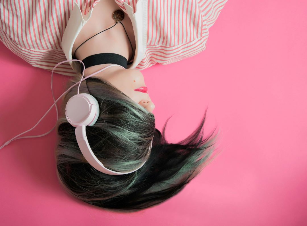 Foto de uma mulher deitada com fone de ouvido um acessório tecnológico.