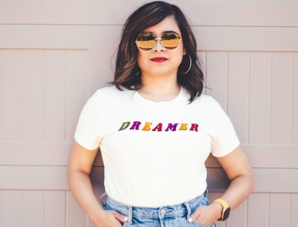 Foto de uma mulher com camiseta e acessórios com a frase sonhadora.