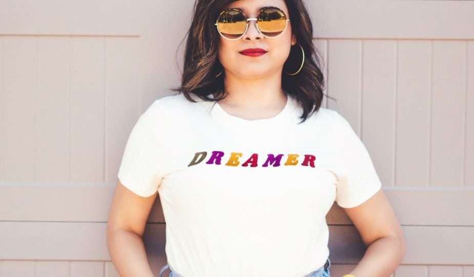 Foto de uma mulher com camiseta e acessórios com a frase sonhadora.