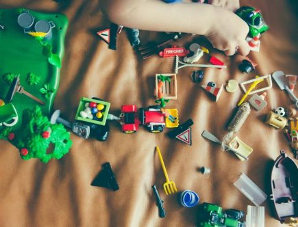 Foto de uma criança brincando com vários brinquedos curtindo as férias das crianças.