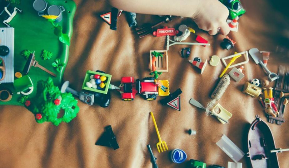 Foto de uma criança brincando com vários brinquedos curtindo as férias das crianças.