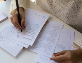 Foto de uma mulher fazendo suas anotações em um planner.